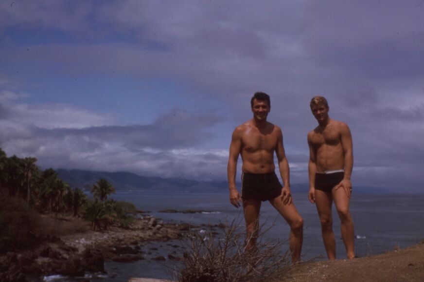 Rock Hudson and a friend in swimsuits, on a cliff ooverlooking the ocean