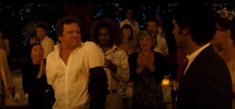 Colin Firth shrugs off his suit jacket as he makes moves towards a young man while dancing at a wedding in a scene from 'Mamma Mia.'
