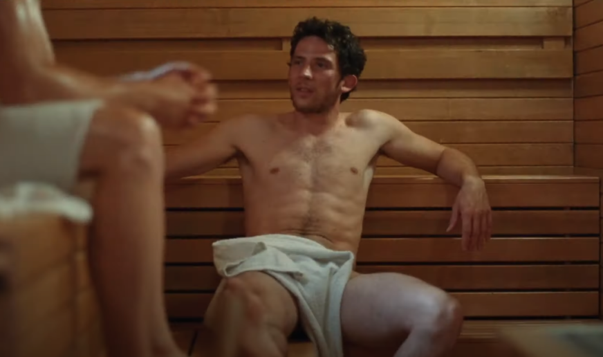 Josh O'Connor wears a towel and is nude in a sauna