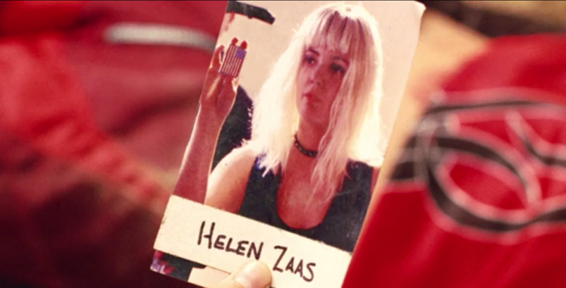 Drew Barrymore, wearing a bleach blonde wig and holding a USA flag lighter, in a polaroid picture labeled "Helen Zaas" in a scene from 'Charlie's Angels: Full Throttle.'
