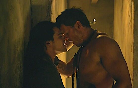 A scene from "Spartacus' in which two muscled gladiators make out against a wall