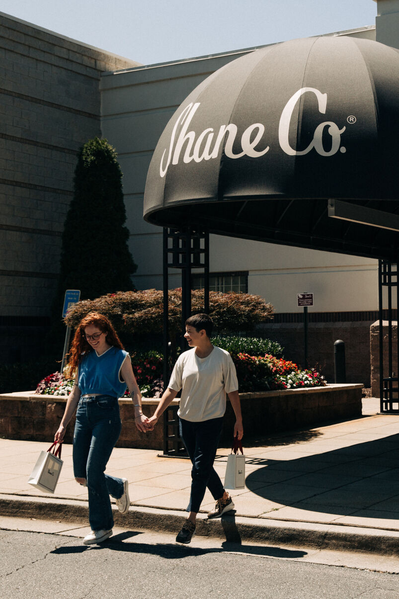 A female couple leaves a Shane Co. jewelry store with new wedding bands.