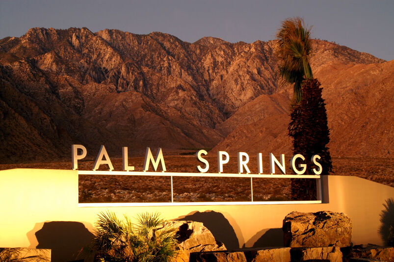 A sign of Palm Springs with a desert background. 