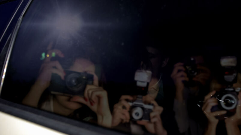 A reflection of paparazzi on a car window. 