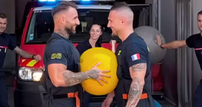 Two firefighters squeeze a yoga ball between them