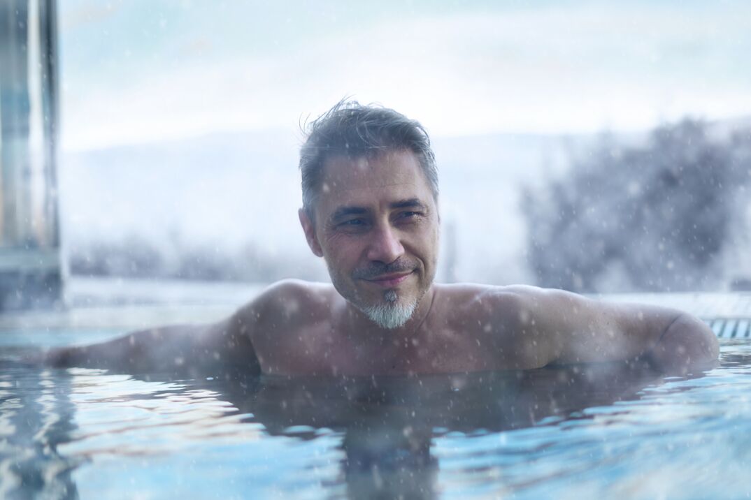Torso of older handsome man with gray hair and goatee in hot tub. 