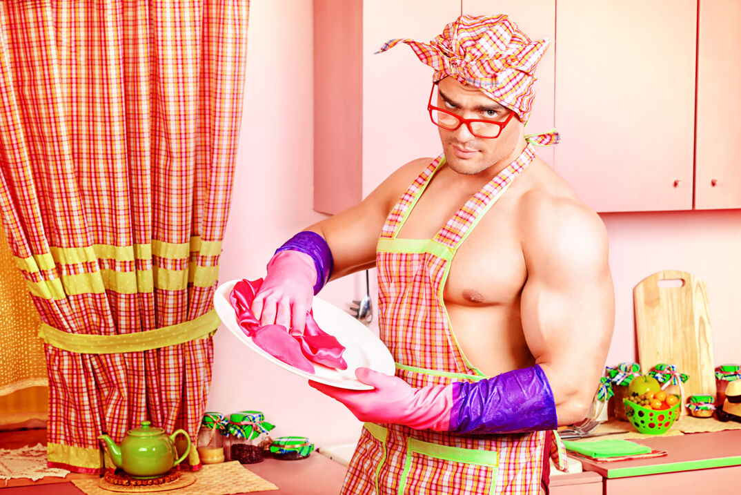 A bodybuilder wearing apron and cleaning accessories. 