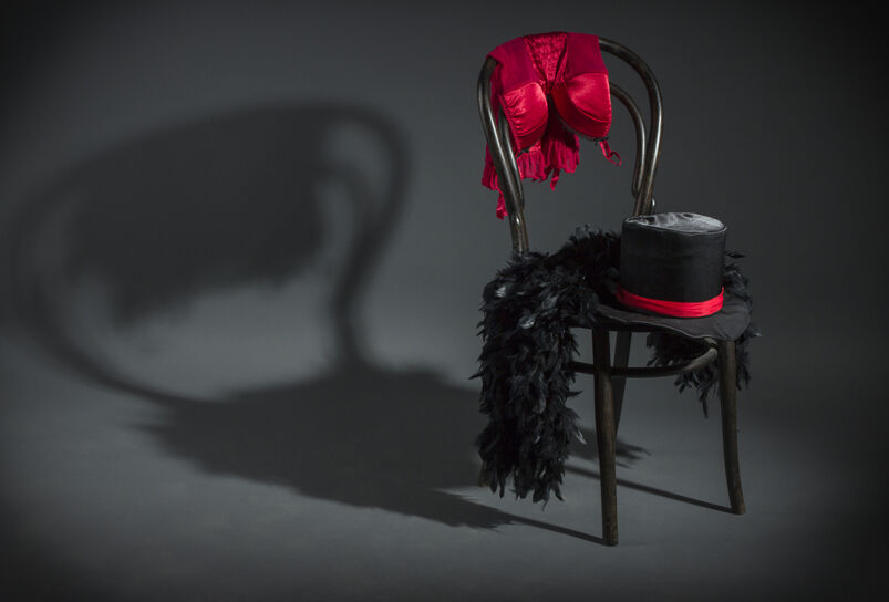 A retro chair with cabaret dancer clothing against a grey background.