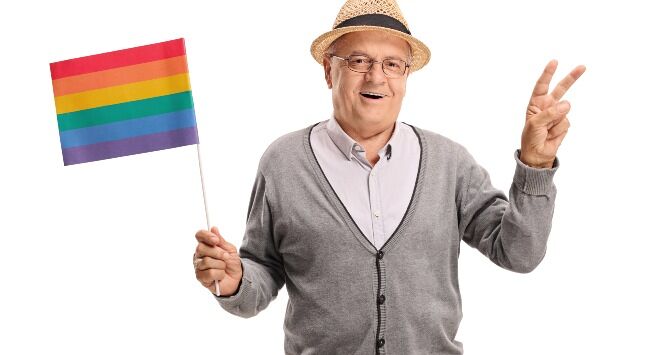 A gay senior holds a rainbow flag