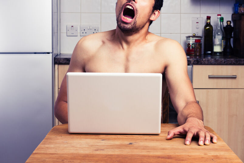 The O-face and other expressions caught on film: Young naked man watching pornography in his kitchen