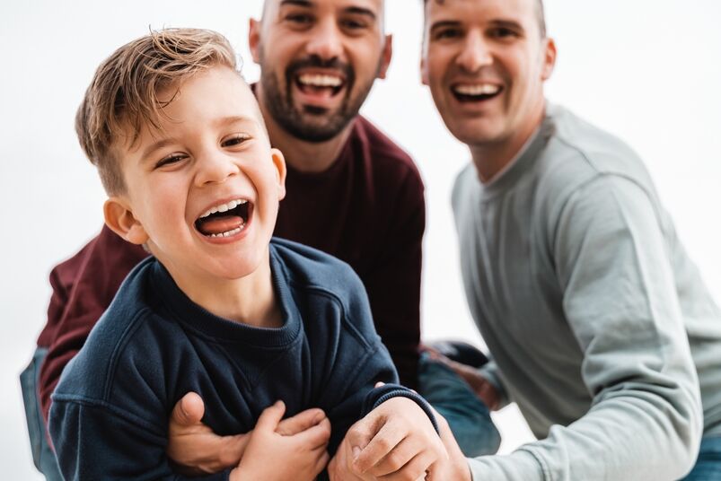 Gay baby names: Gay male parents having fun with their son outdoor - Focus on kid boy face