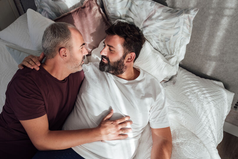 Fax sex and chubby chasing: Couple of gay men together in bed at home Lying on the mattress and looking at each other's faces