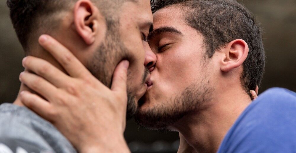 Two men kiss each other