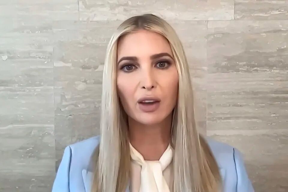 Ivanka Trump in a white shirt and blue blazer standing against a marble wall.