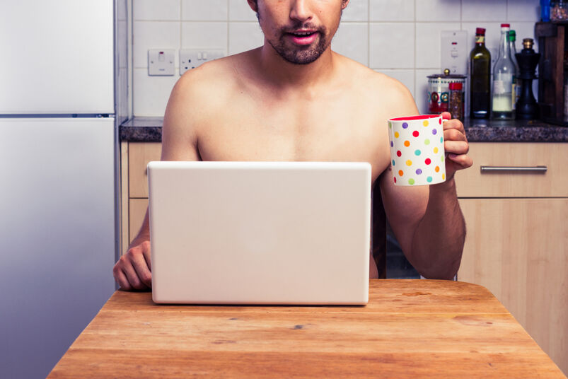 Naked man using laptop at home