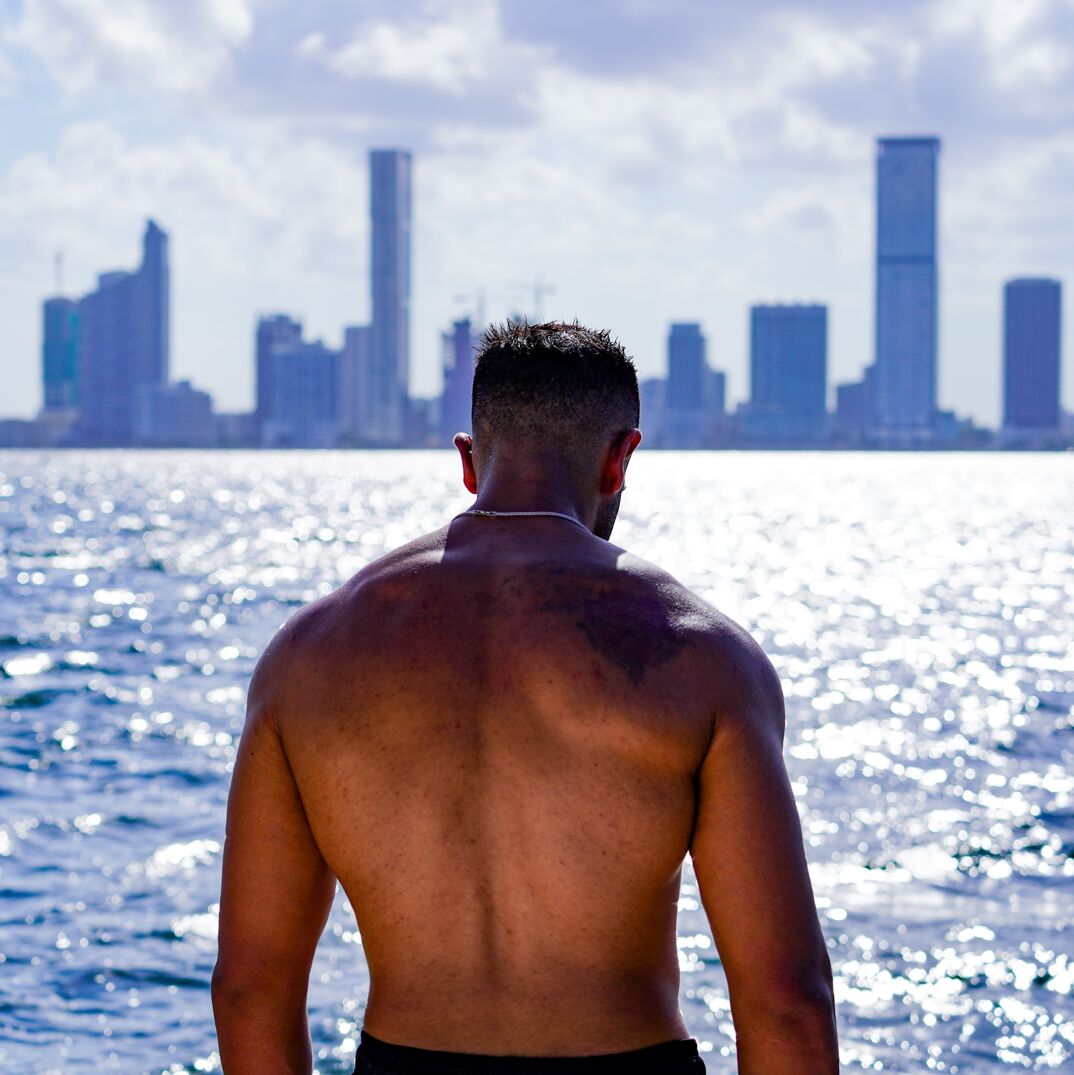 A man looking into the ocean with the Miami skyline. 