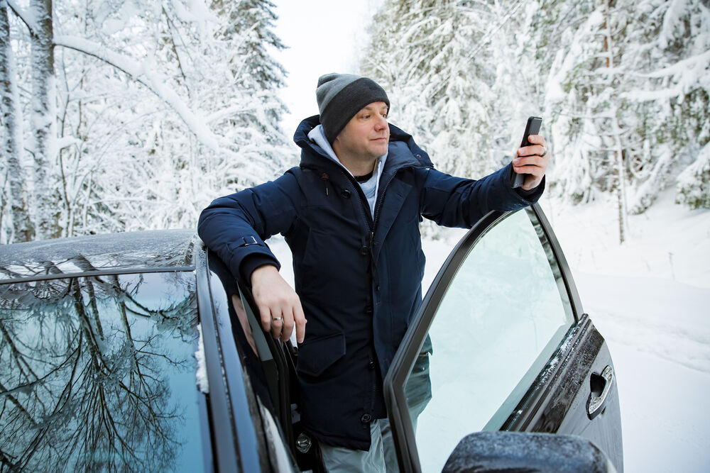 Man looking at phone while driving through snow