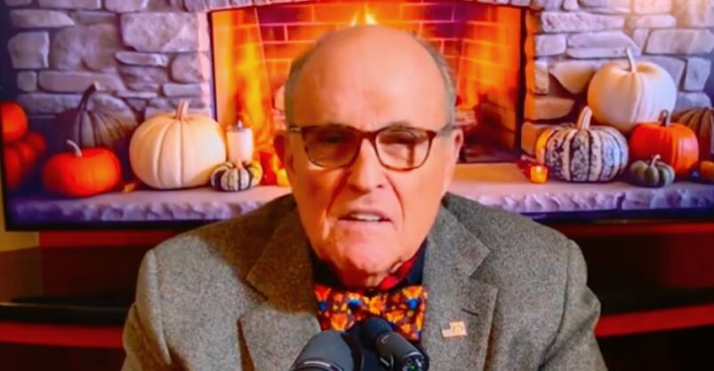 Rudy Giuliani sitting in front of a fireplace, looking like his head is on fire. 