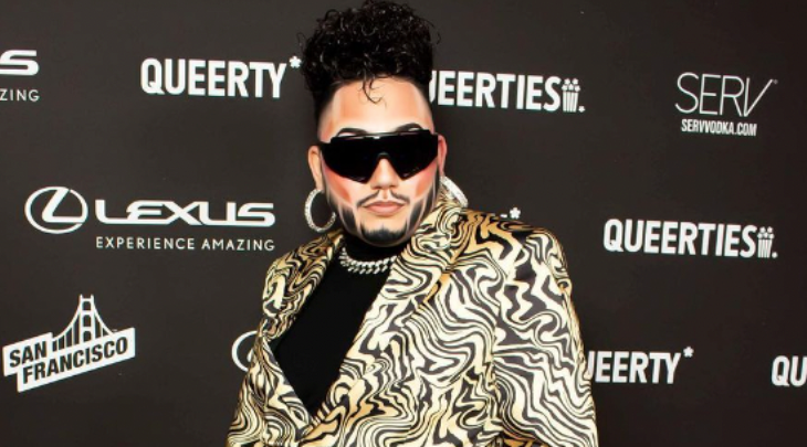 Drag king tenderoni poses in sunglasses and a striped animal print suit suit