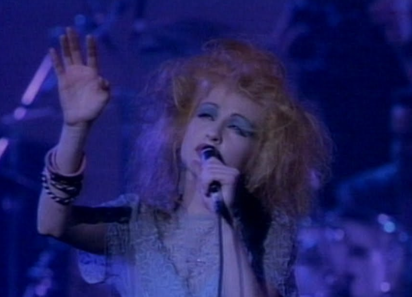 Cyndi Lauper performing under a halo of blue light