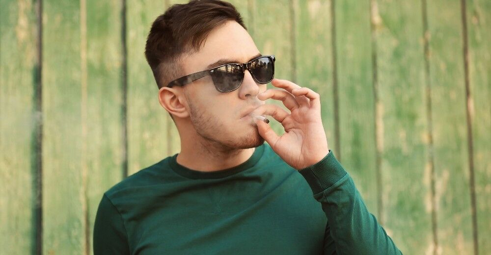 A man smokes a roll-up cigarette