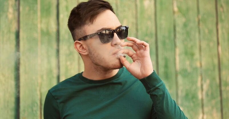 A man smokes a roll-up cigarette