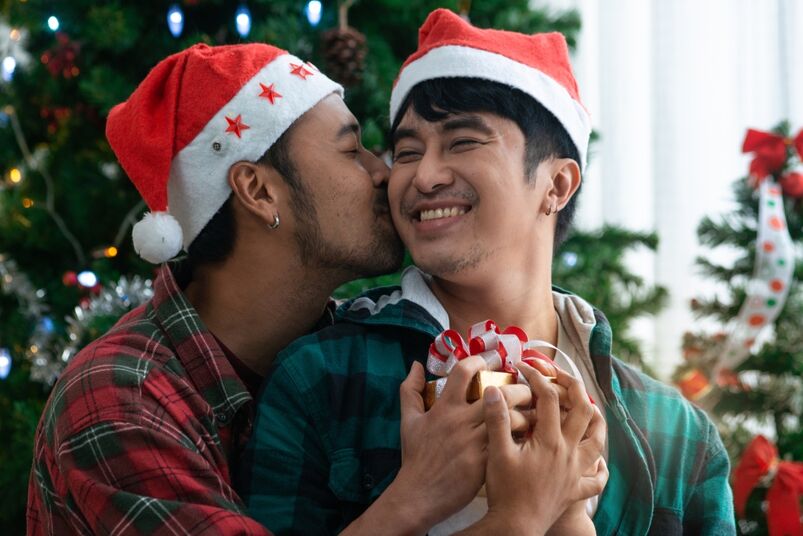 Gay couple exchanging presents in front of a Christmas tree