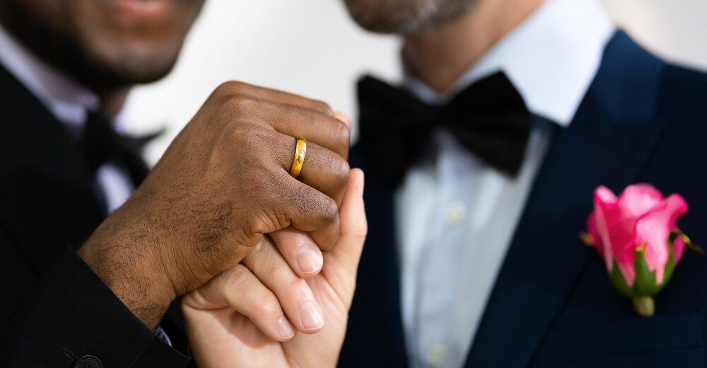 A gay couple hold hands as they wed