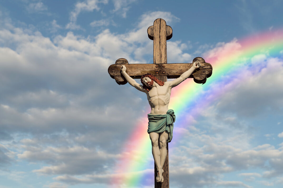 Crucifix with rainbow in the blue sky