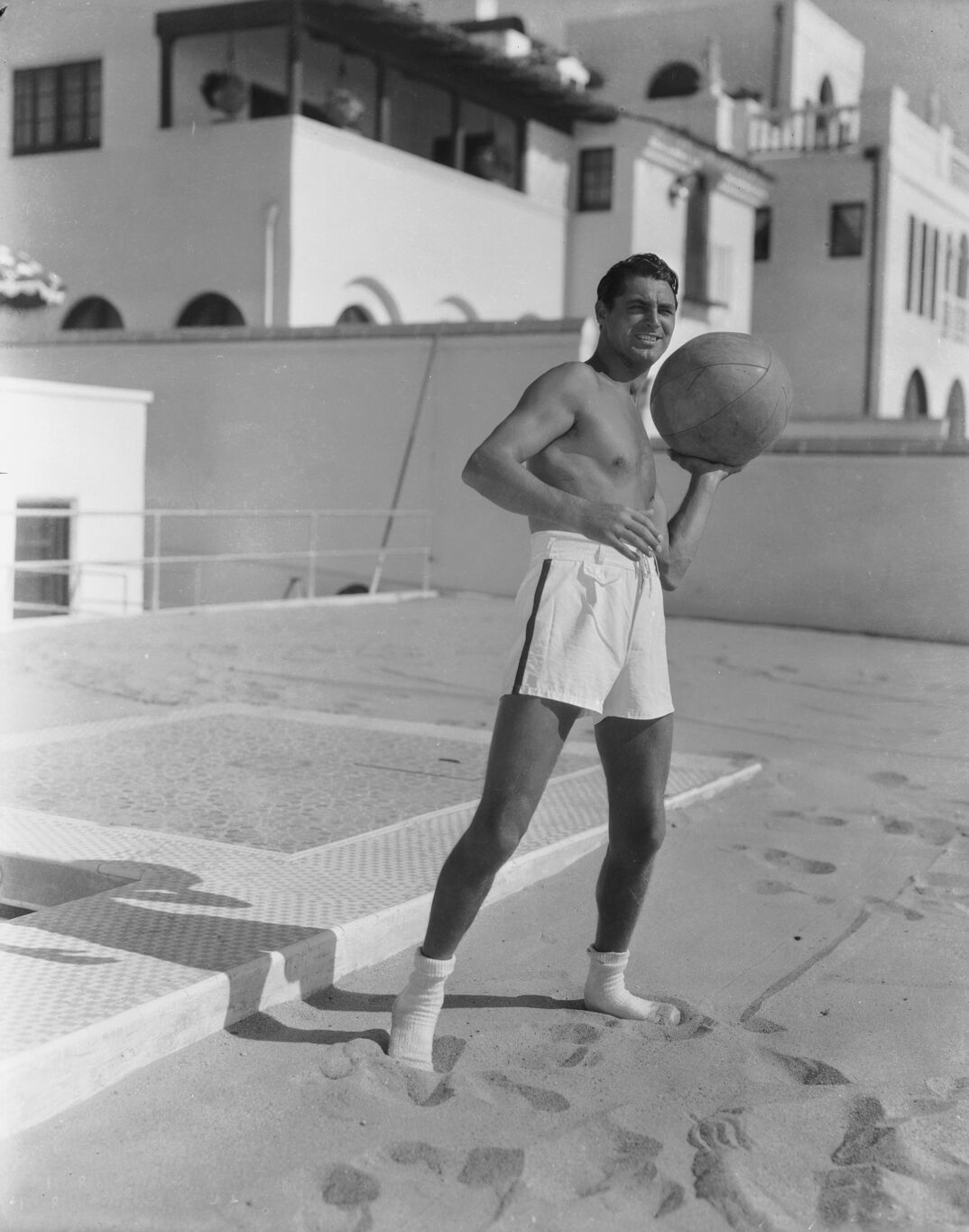 1935:  British born actor Cary Grant (1904 - 1986), born Archibald Leach, playing with a ball at the beach house he shared with the American actor, Randolph Scott.  (Photo via John Kobal Foundation/Getty Images)
