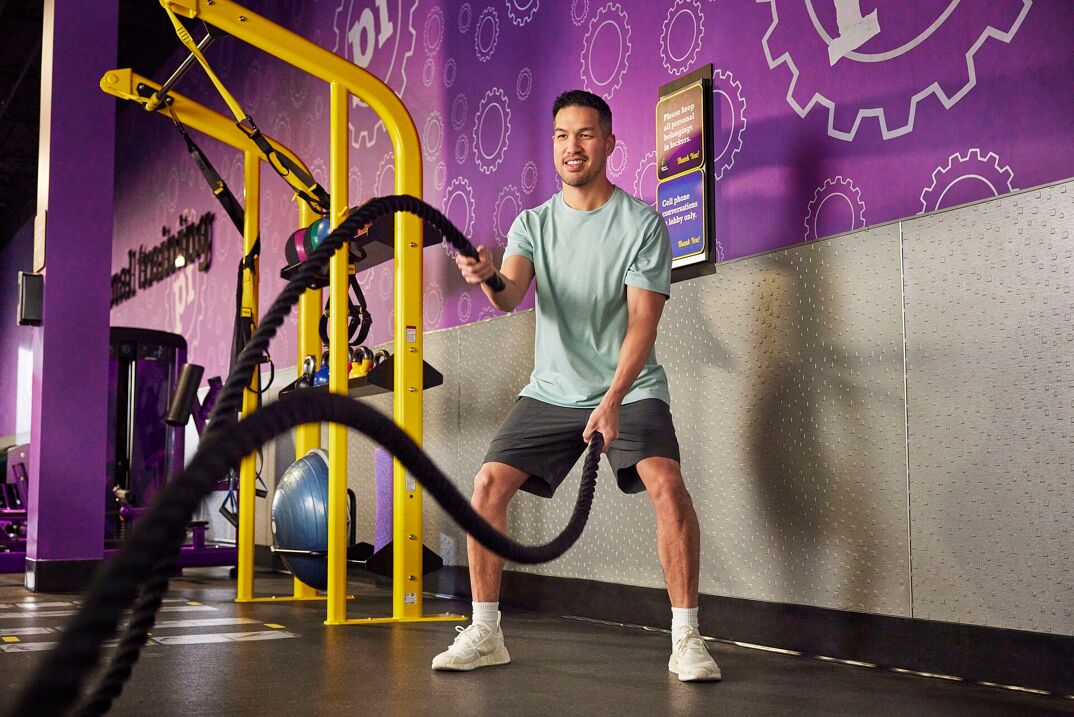 Man using battle ropes at Planet Fitness.