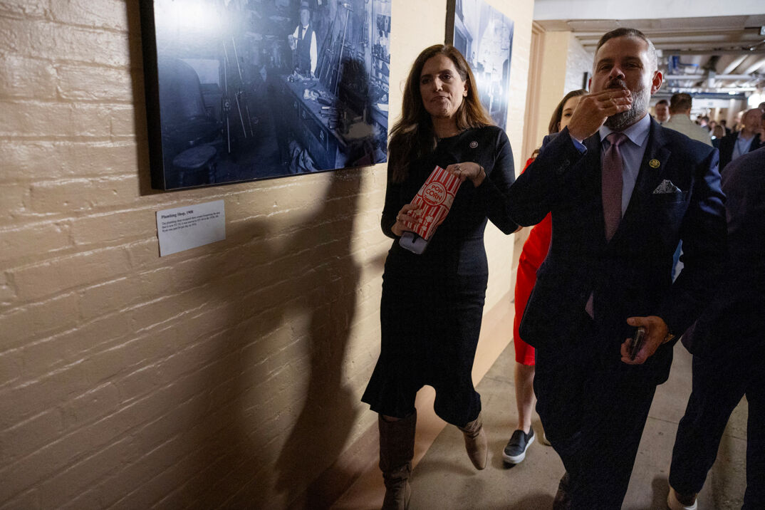 Nancy Mace walking down the walls of Congress eating a bag of popcorn.