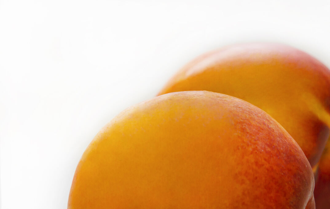 A zoomed-in image of a furry, yellow and pink peach, posed in the corner to resemble buttocks.