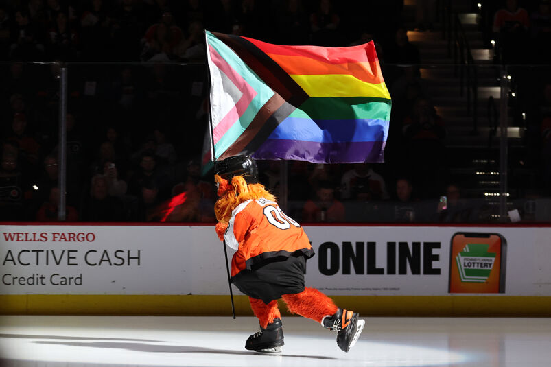 Philadelphia Flyers mascot Gritty holding the Progress Flag on the ice. 