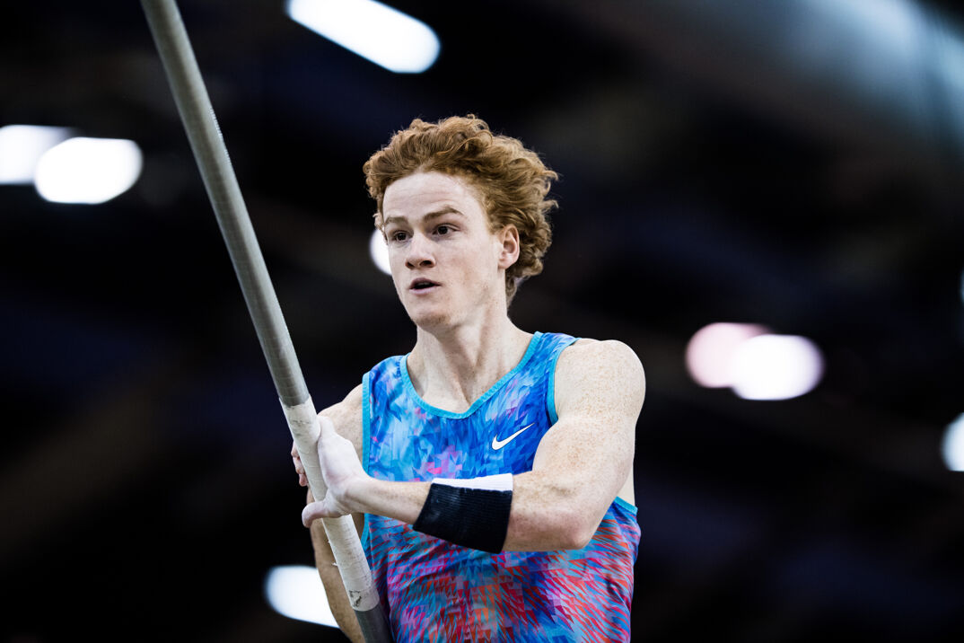 Pole vaulter Shawn Barber competing in a multi-colored Nike tank top. 