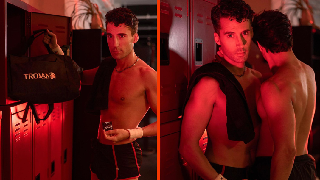 Two-panel image. On the left, Jackie Cox stands shirtless in red light against a locker. He's lean and toned with dark hair and looks into the camera holding a pack of condoms and a bag reading "Trojan." On the right, he's pictured without the bag, smiling seductively as another toned shirtless man, whose face is hidden, leans into him.