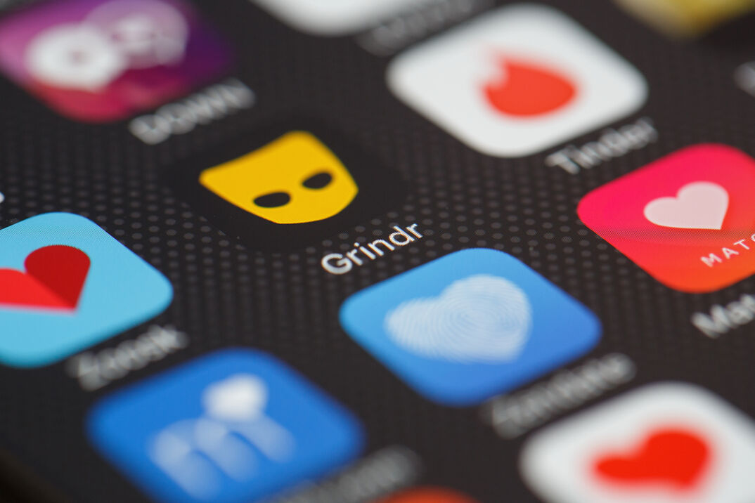 The orange "Grindr" app logo is seen amongst other dating apps on a mobile phone screen.