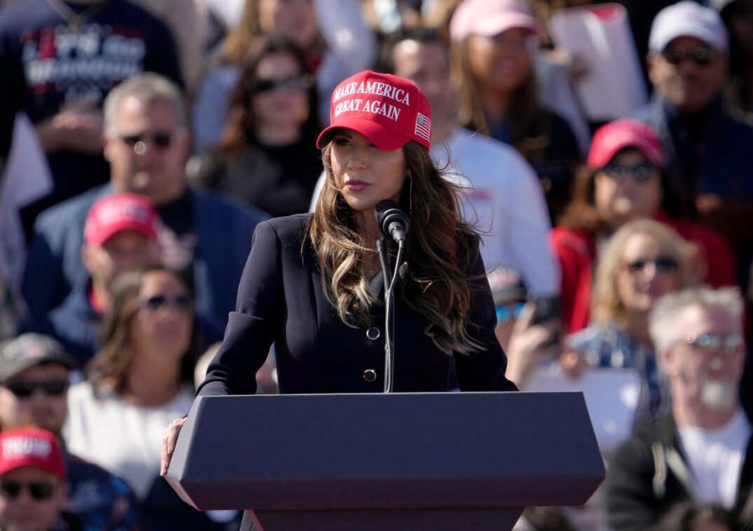 Kristi Noem wearing a red "Make America Great Again" hat. 