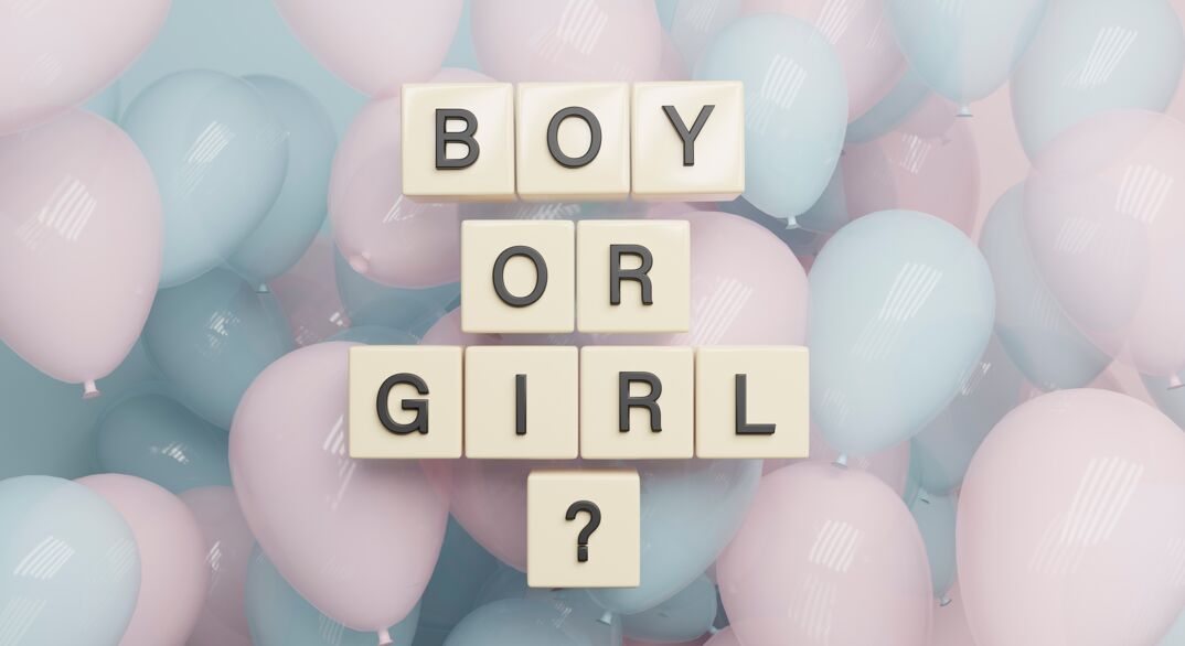 An array of pastel pink and blue balloons form the backdrop for scrabble-like tiles spelling out 'BOY OR GIRL?' with a question mark tile at the bottom center, illustrating the anticipation of a gender reveal.