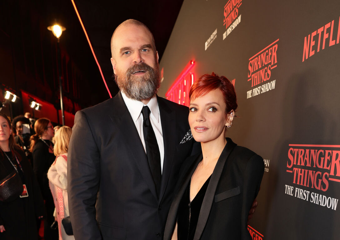 David Harbour and ex-wife Lily Allen stand in front of a step and repeat at a red carpet event.